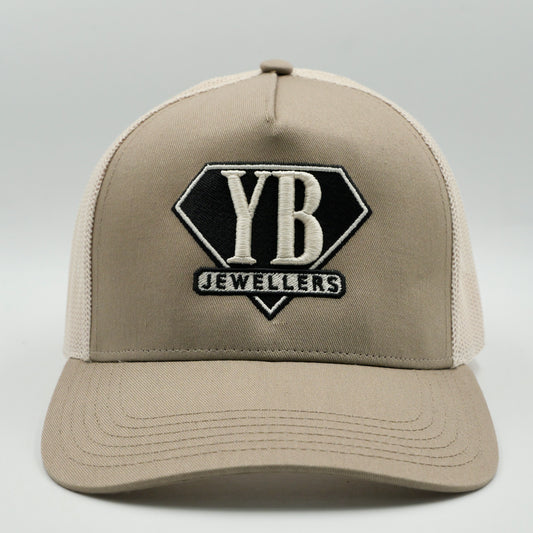 Beige cap with YB Jewellers logo on a gray background