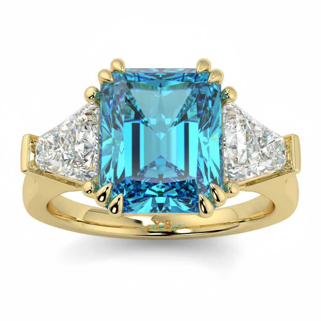 Gold ring with a blue gemstone and diamond accents on a white  background Introducing daisy radient square blue lab grown diamond engagement ring set in yellow gold with lab grown side diamonds 18k yellow gold coloured diamond ring 