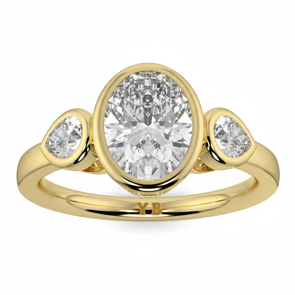 Gold ring with three diamonds on a white background oval and pear diamond trilogy ring yb jewellers best selling design and engagement rings 