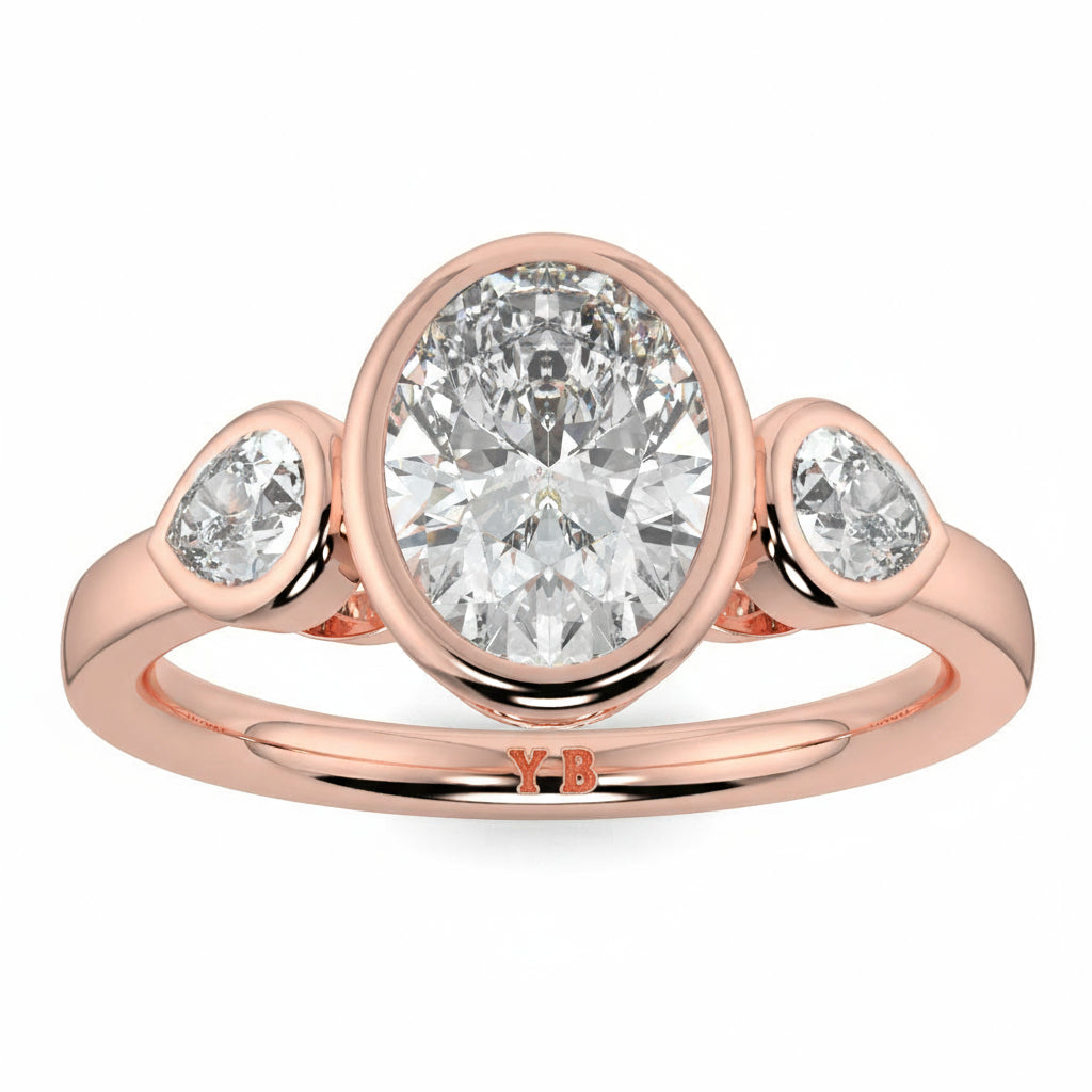 Rose gold ring with three diamonds on a white background, featuring the brand oval and pear diamond trilogy ring yb jewellers best selling design and engagement rings 