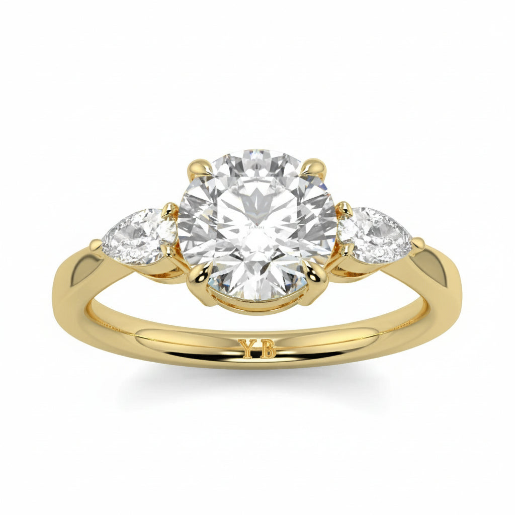 Gold ring with a central diamond and two smaller diamonds on a white background yb jewellers 3 stone trilogy engagement ring round and pear shape best selling design trending diamond ring