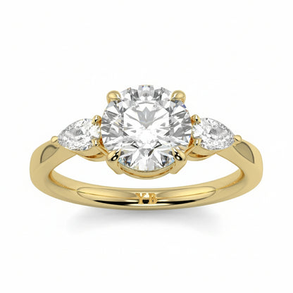 Gold ring with a central diamond and two smaller diamonds on a white background yb jewellers 3 stone trilogy engagement ring round and pear shape best selling design trending diamond ring