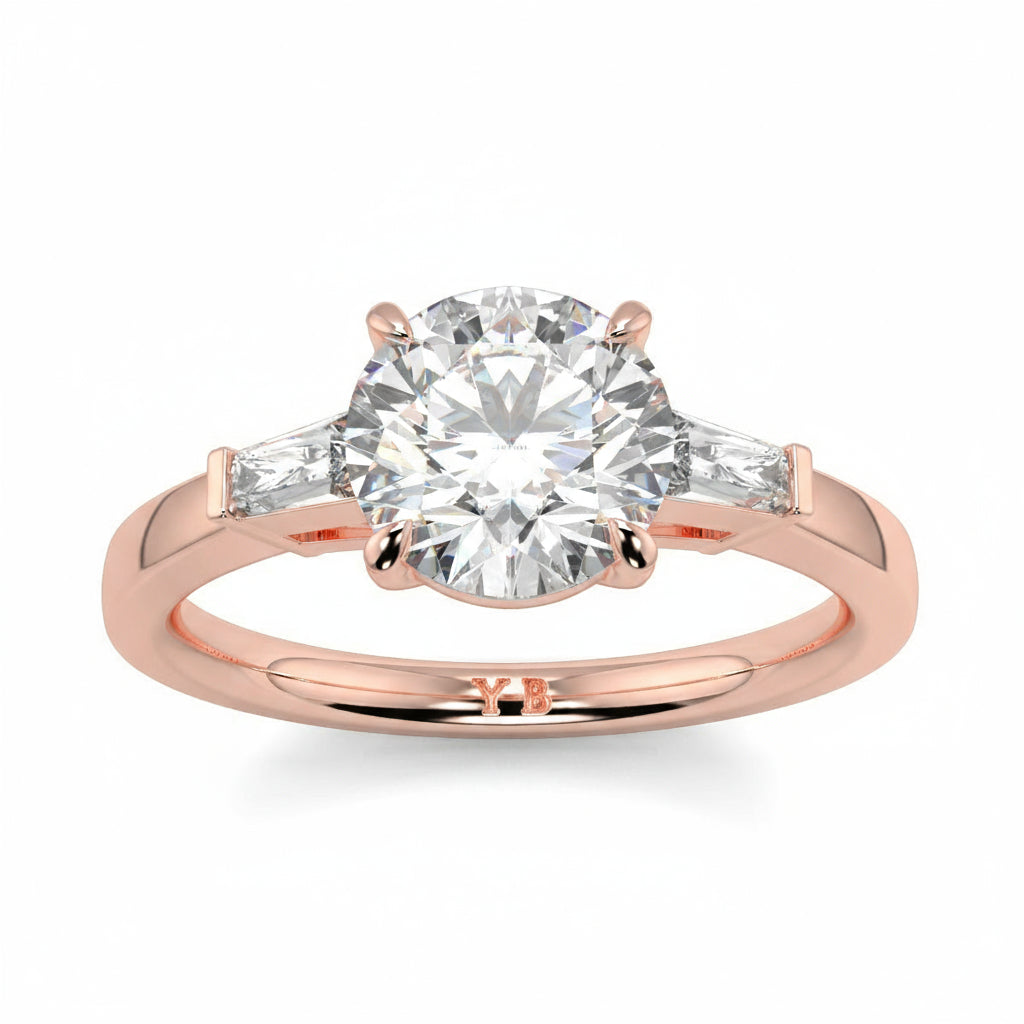 Rose gold ring with a large diamond and smaller diamonds on the sides, branded 'LUVONE'. yb_jewellers_3_stone_trilogy_engagement_ring_round_and_pear_shape_best_selling_design_trending_diamond_ring