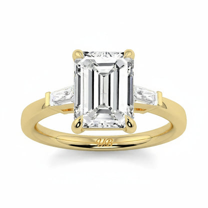 Gold ring with emerald-cut diamond on a white background yb_jewellers_3_stone_trilogy_engagement_ring_round_and_pear_shape_best_selling_design_trending_diamond_ring