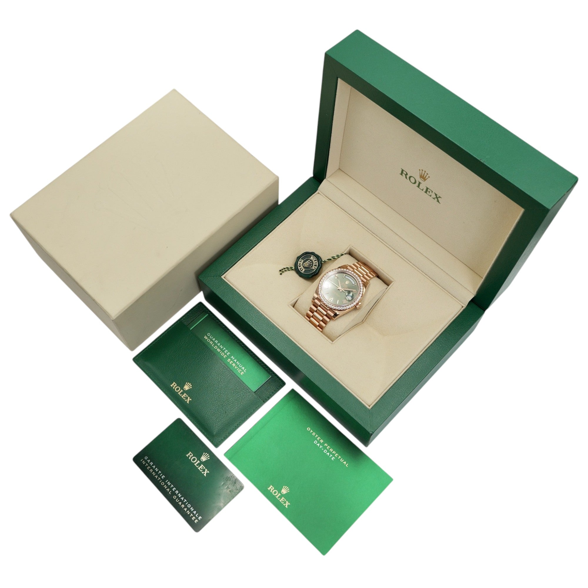 Rolex watch in an open green and beige box with accessories on a white background