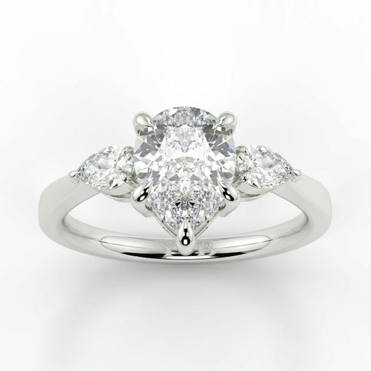 Diamond ring with a central pear-shaped diamond and two smaller diamonds on a white background _yb_jewellers_3_stone_trilogy_engagement_ring_round_and_pear_shape_best_selling_design_trending_diamond_ring