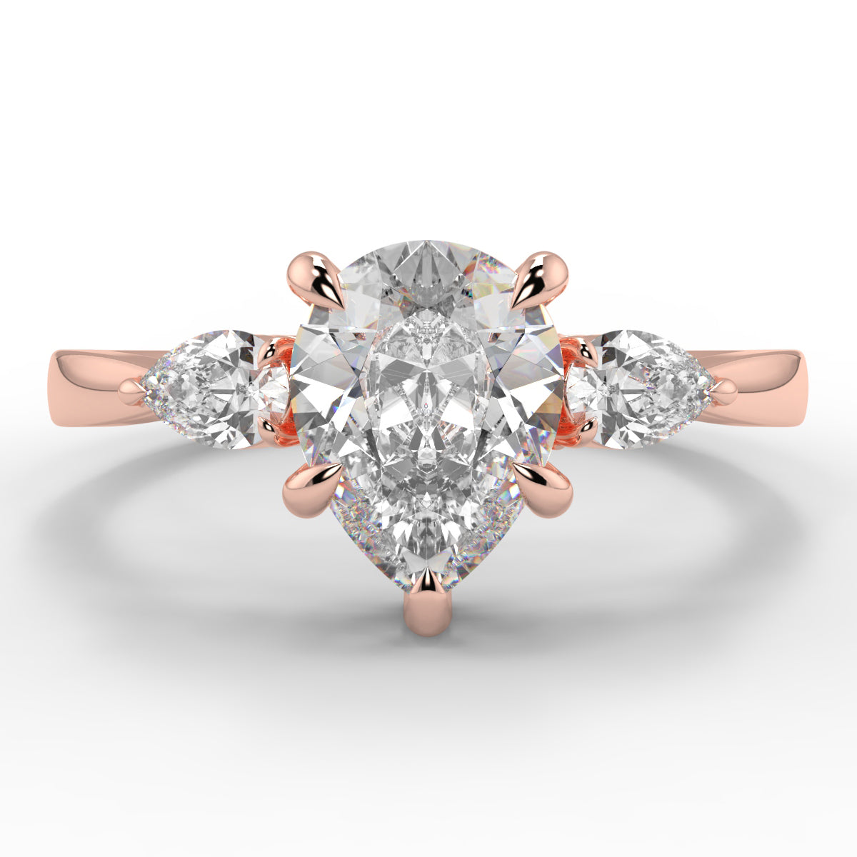 Rose gold ring with a large diamond and smaller diamonds on the sides against a white background _yb_jewellers_3_stone_trilogy_engagement_ring_round_and_pear_shape_best_selling_design_trending_diamond_ring