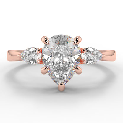 Rose gold ring with a large diamond and smaller diamonds on the sides against a white background _yb_jewellers_3_stone_trilogy_engagement_ring_round_and_pear_shape_best_selling_design_trending_diamond_ring