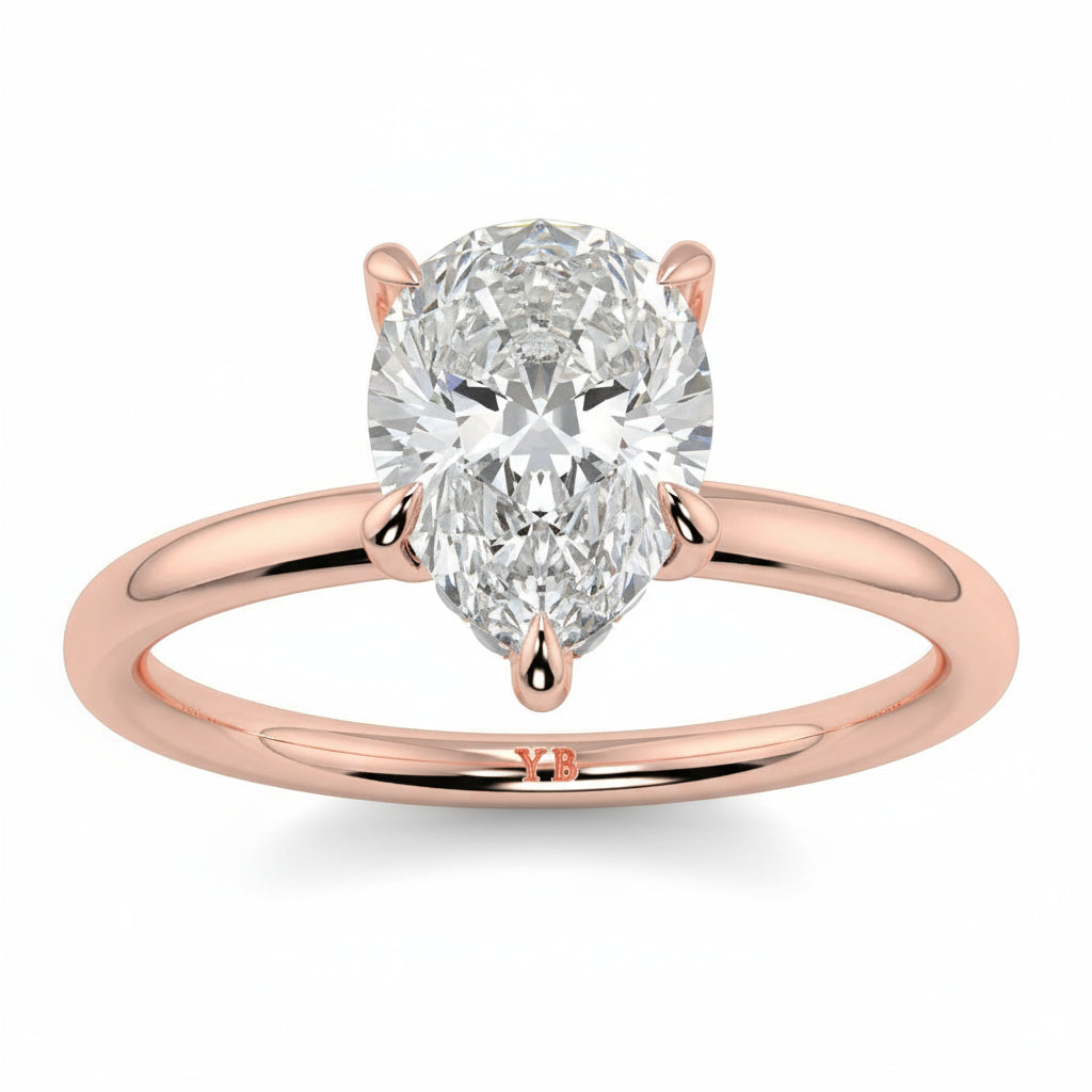 Rose gold ring with a pear-shaped diamond on a white background _yb_jewellers_solitaire_engagement_ring_best_selling_design_cushion_shape_diamond_4_claw_with_a_slim_band