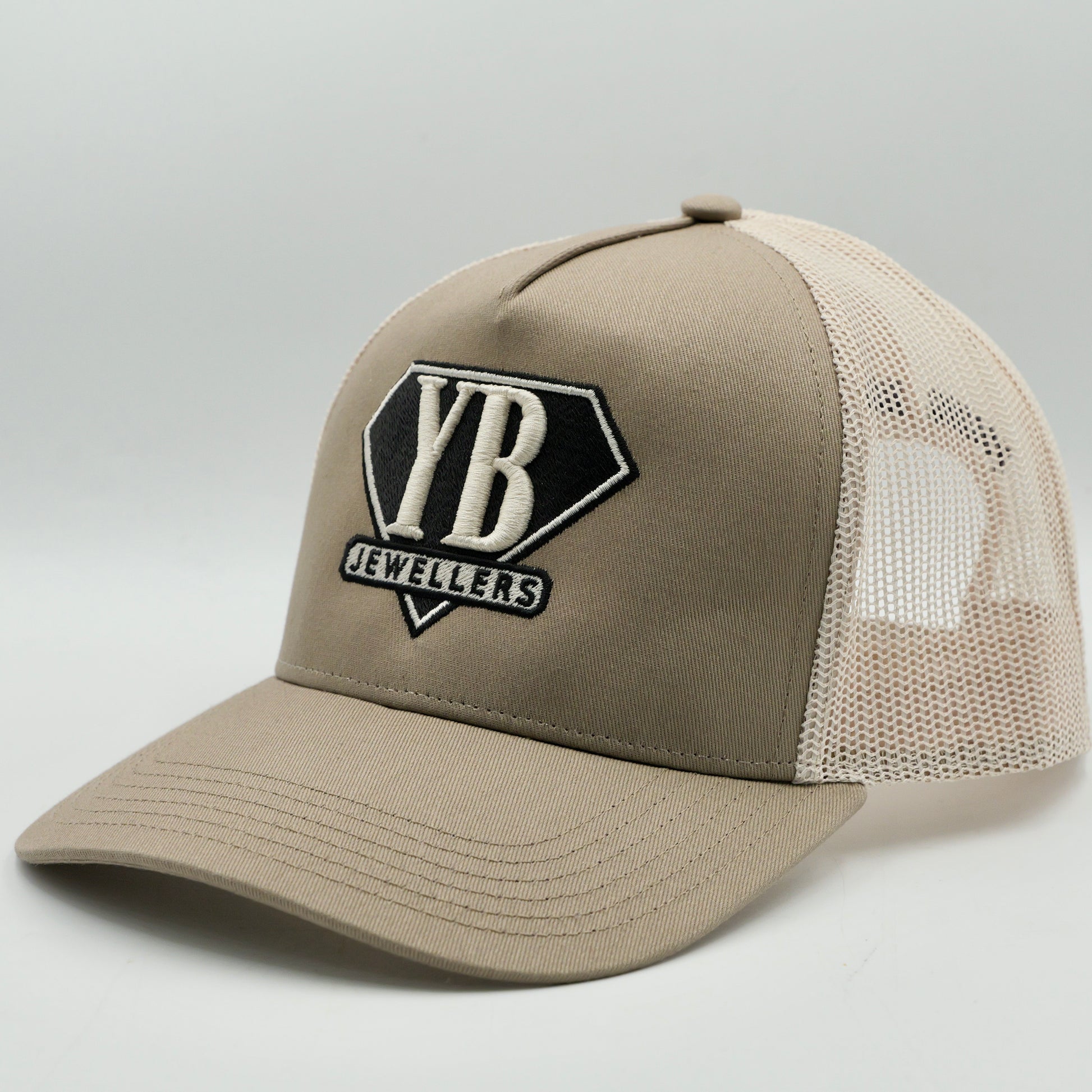 Beige trucker cap with 'YB Jewellers' logo on a light gray background