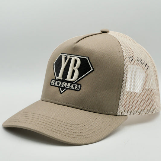 Beige trucker cap with 'YB Jewellers' logo on a light gray background