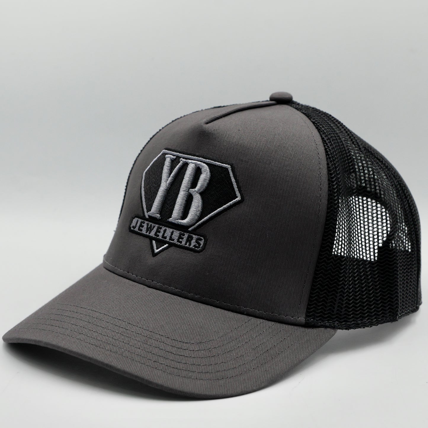 Gray trucker cap with black mesh back and visible branding on a light gray background